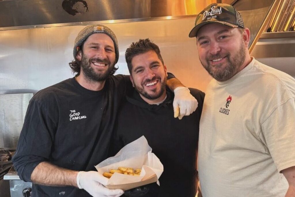 The Cluckies Hot Chicken crew smiling in the kitchen with a tray of fries