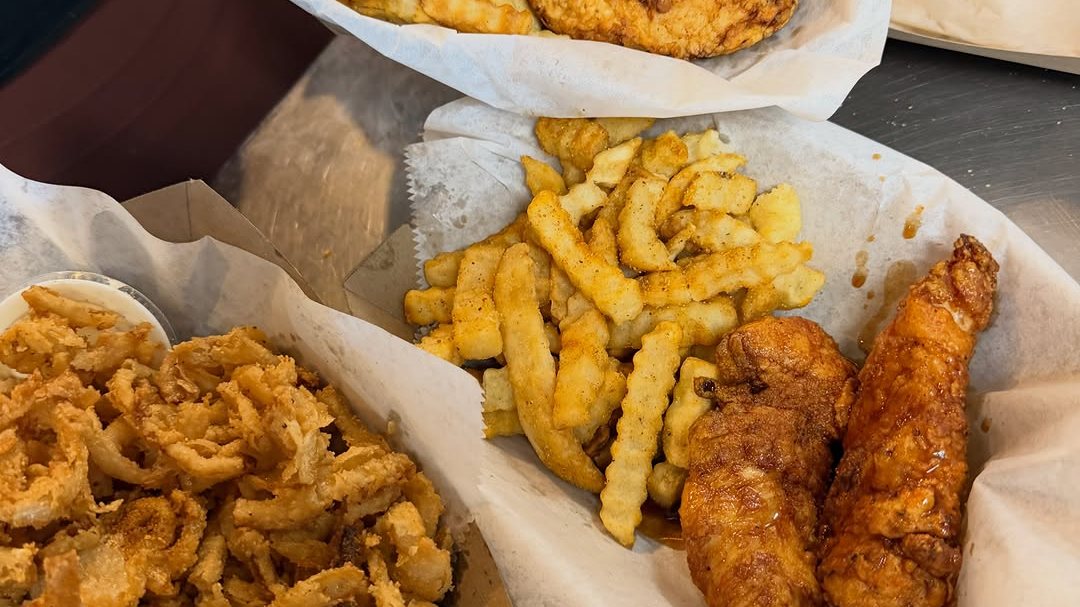 Cluckies beef tallow fried chicken tenders with crinkle fries in paper-lined baskets